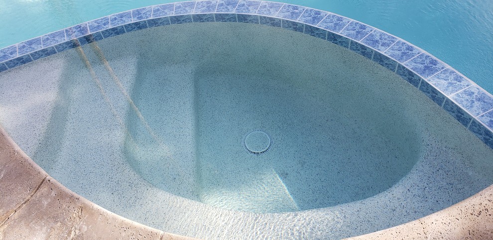 Diseño de piscina infinita mediterránea de tamaño medio tipo riñón en patio trasero con suelo de baldosas