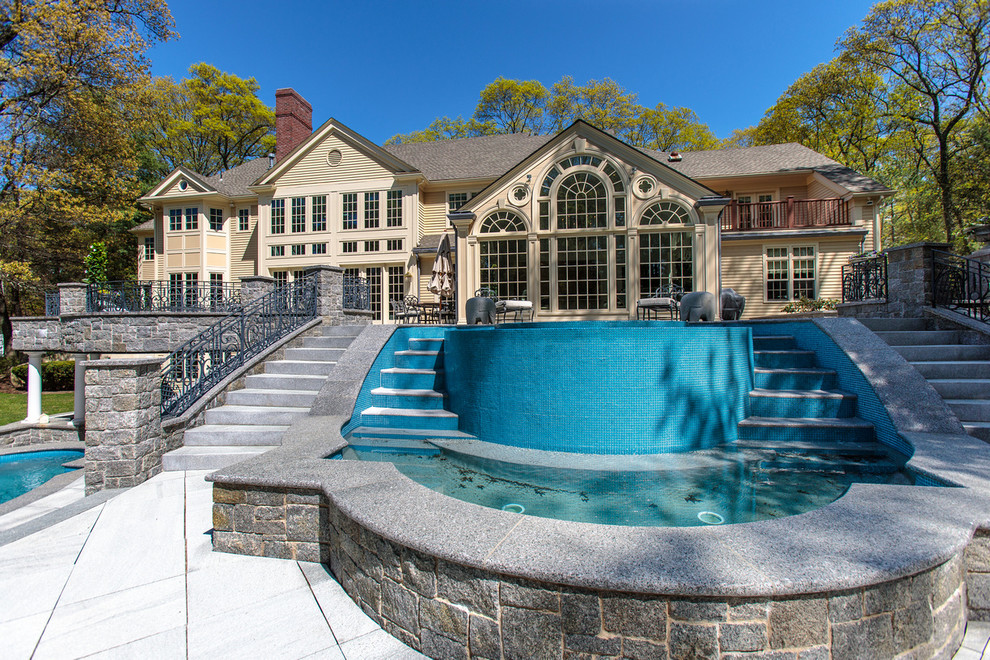 Photo of a large traditional back custom shaped natural swimming pool in Boston with a water feature and concrete paving.