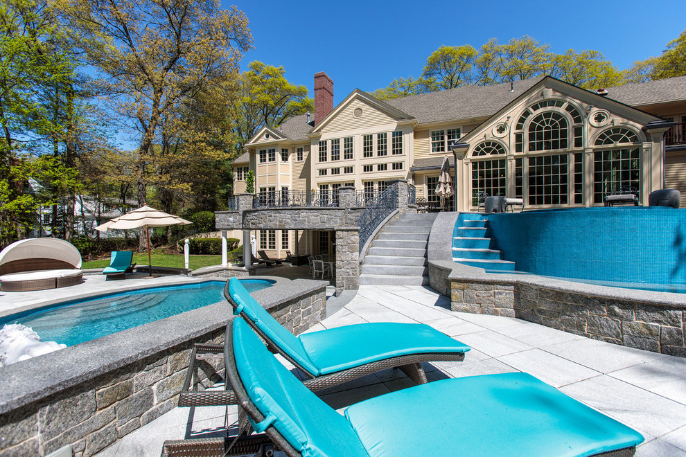 Foto de piscina con fuente natural clásica grande a medida en patio trasero con adoquines de hormigón