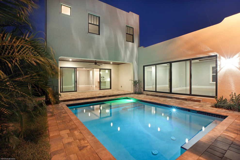 Immagine di una piscina minimalista personalizzata di medie dimensioni e dietro casa con fontane e pavimentazioni in pietra naturale