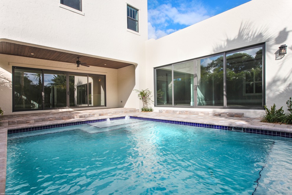 Mittelgroßer Mid-Century Pool hinter dem Haus in individueller Form mit Wasserspiel und Natursteinplatten in Miami