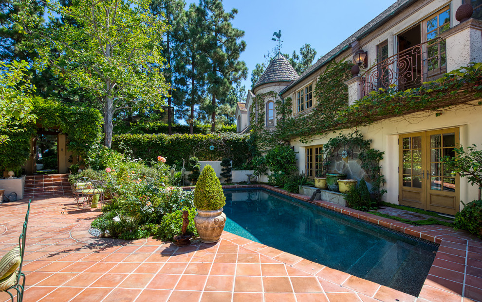 Design ideas for an expansive rustic courtyard custom shaped swimming pool in Orange County with a water feature and tiled flooring.