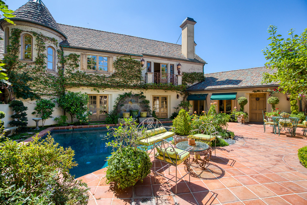This is an example of an expansive rustic courtyard custom shaped swimming pool in Orange County with a water feature and tiled flooring.