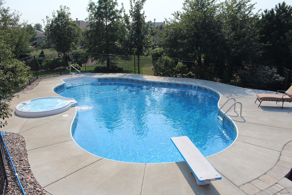 Ispirazione per una grande piscina tradizionale personalizzata dietro casa con lastre di cemento e una vasca idromassaggio