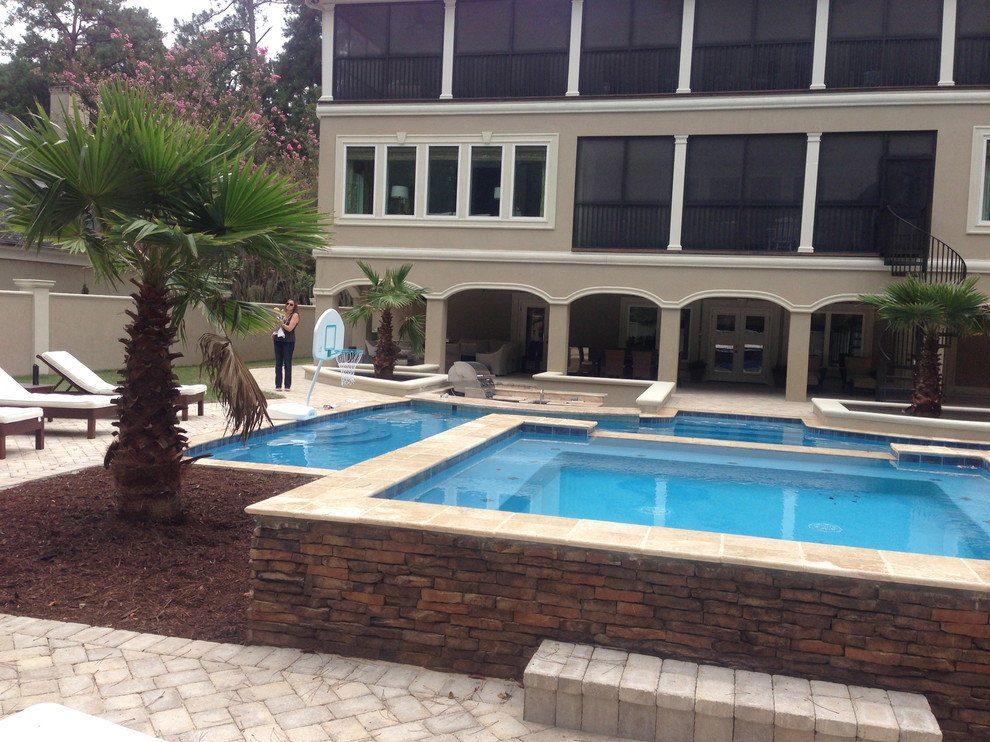 Modelo de piscinas y jacuzzis alargados clásicos grandes rectangulares en patio trasero con adoquines de hormigón