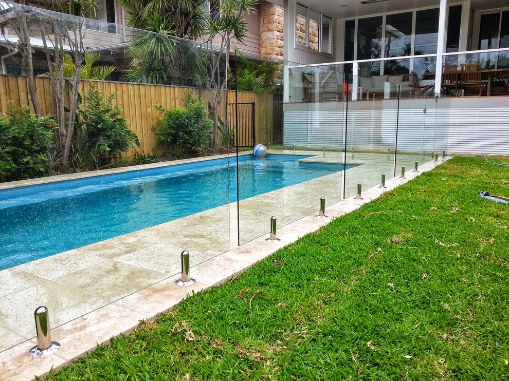Example of a small beach style backyard stone and rectangular lap pool design in Sydney
