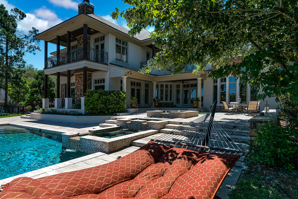 Foto de piscinas y jacuzzis clásicos grandes a medida en patio trasero con adoquines de piedra natural
