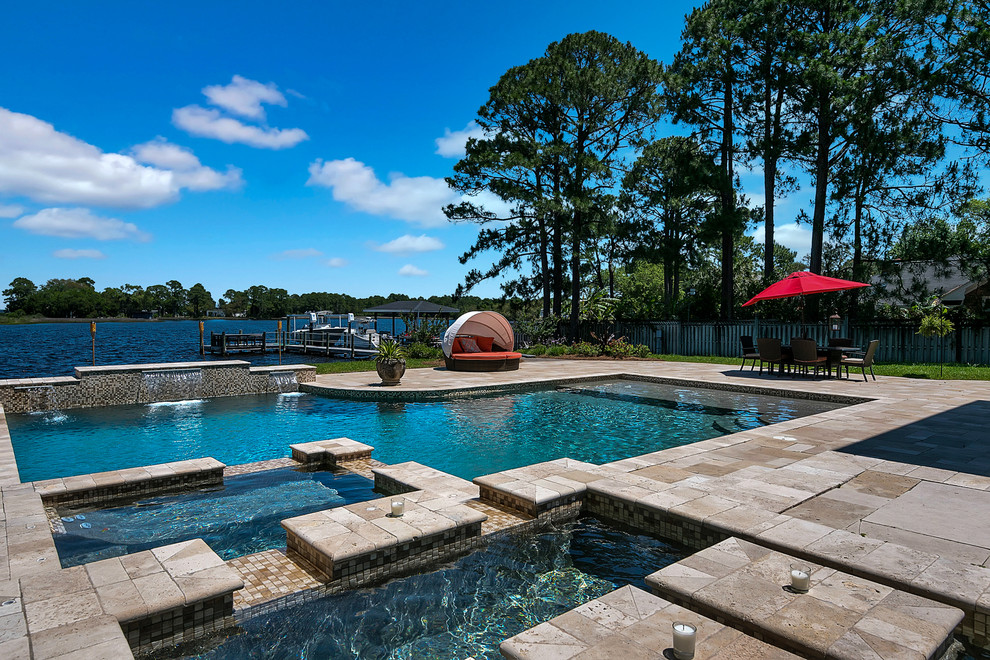 Ispirazione per una grande piscina chic personalizzata dietro casa con una vasca idromassaggio e pavimentazioni in pietra naturale