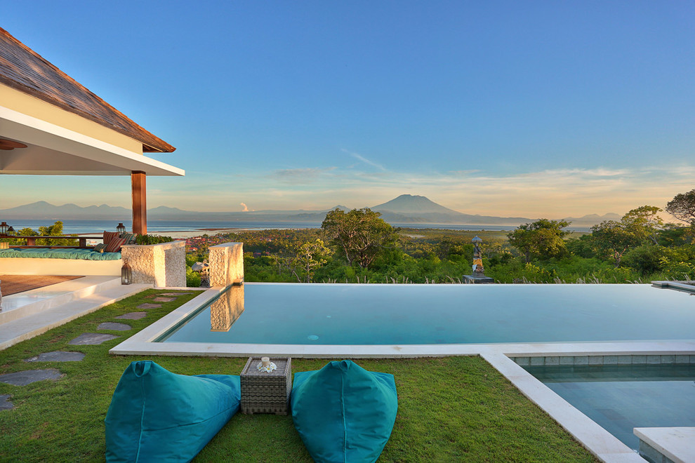 Imagen de casa de la piscina y piscina infinita exótica grande rectangular en patio trasero con adoquines de piedra natural