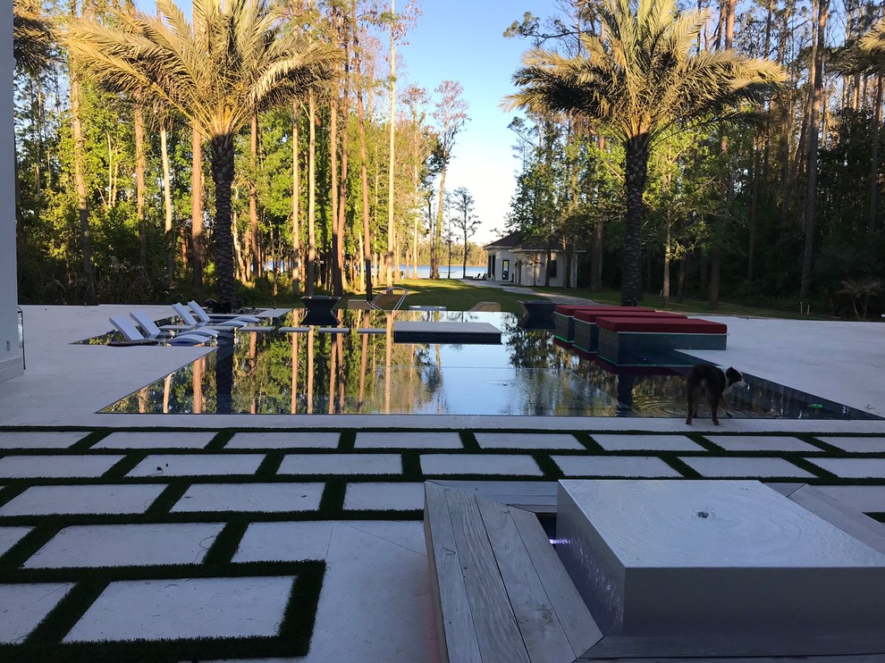 Ispirazione per un'ampia piscina a sfioro infinito moderna personalizzata dietro casa con fontane