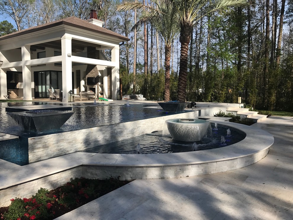 Immagine di un'ampia piscina a sfioro infinito moderna personalizzata dietro casa con fontane