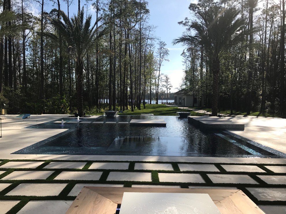 Photo of an expansive modern back custom shaped infinity swimming pool in Orlando with a water feature.