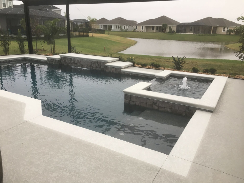На фото: большой естественный бассейн произвольной формы на заднем дворе в стиле модернизм с джакузи и покрытием из бетонных плит