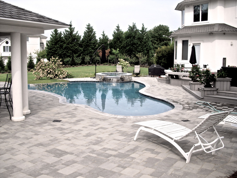Inspiration for a large contemporary backyard brick and custom-shaped hot tub remodel in Other