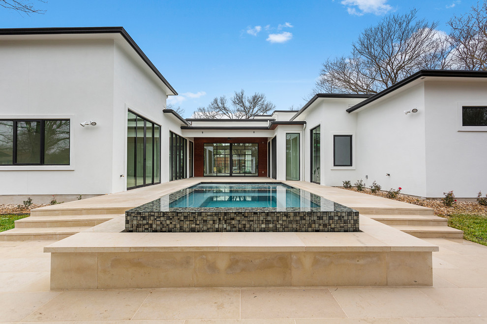 Mittelgroßer Moderner Pool hinter dem Haus in rechteckiger Form mit Wasserspiel und Natursteinplatten in Austin