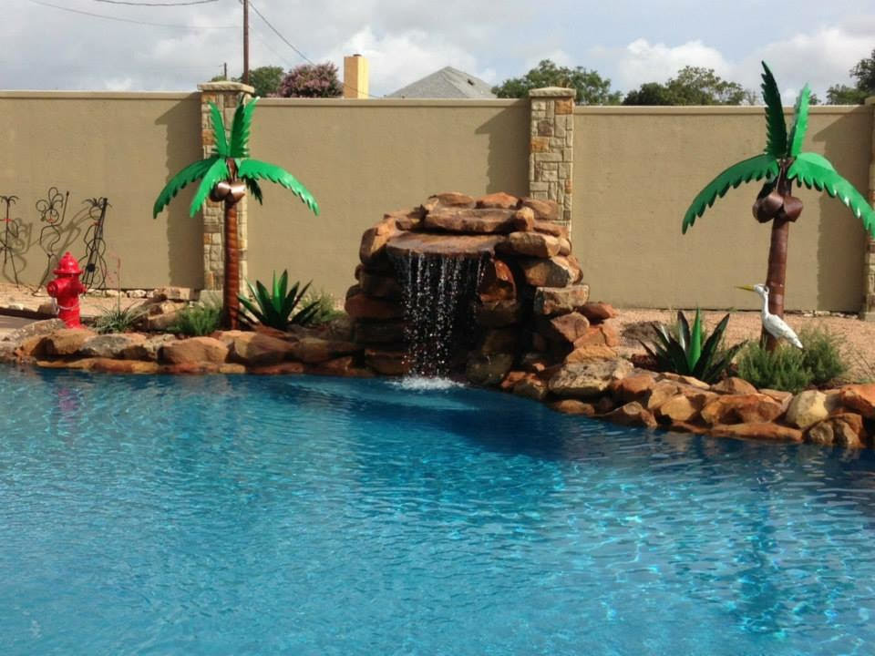 Modelo de piscina con fuente alargada de estilo americano grande a medida en patio trasero con gravilla