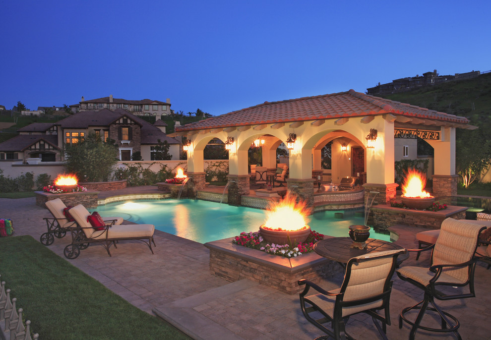 Large tuscan backyard concrete paver and custom-shaped pool fountain photo in Los Angeles