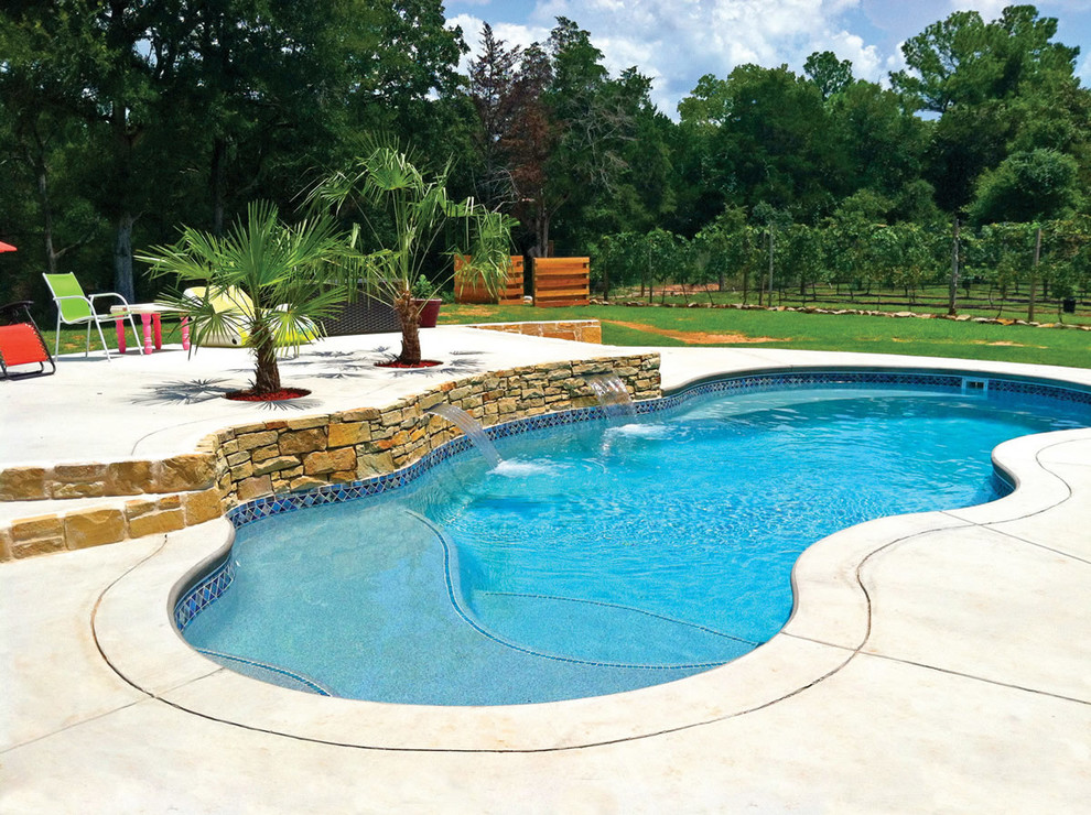 Diseño de piscina con fuente natural marinera de tamaño medio a medida en patio trasero con losas de hormigón