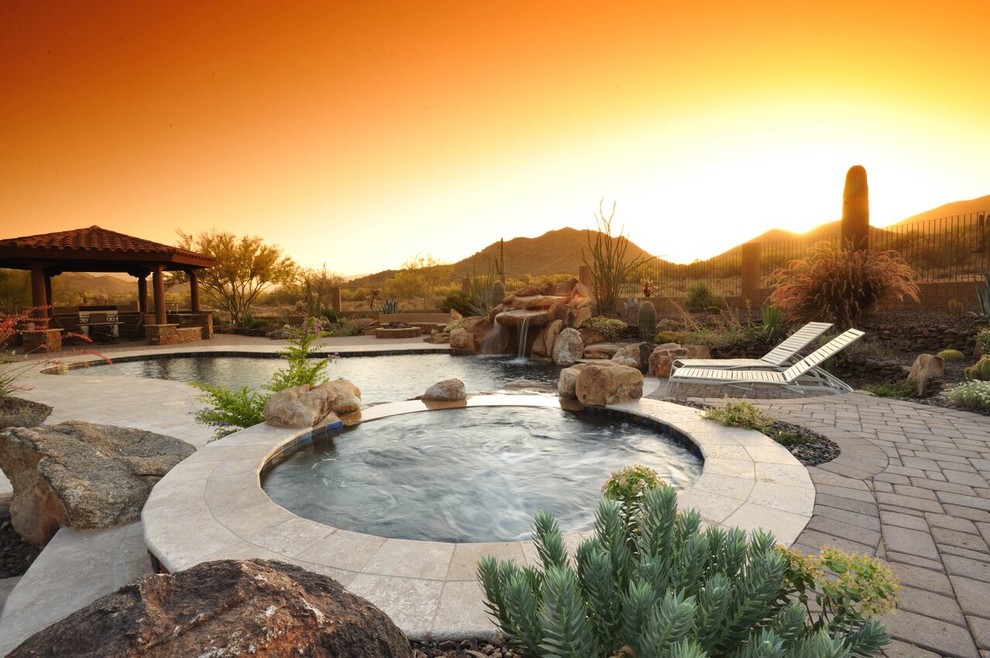 Идея дизайна: большой естественный бассейн произвольной формы на заднем дворе с джакузи и мощением клинкерной брусчаткой