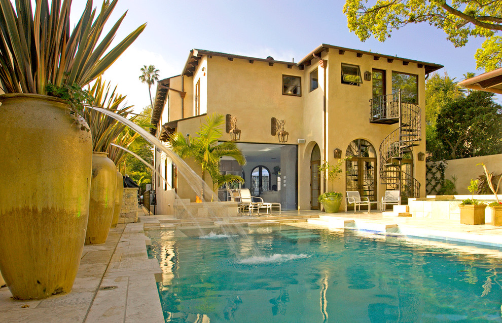 Diseño de piscina con fuente elevada clásica grande rectangular en patio trasero con suelo de baldosas