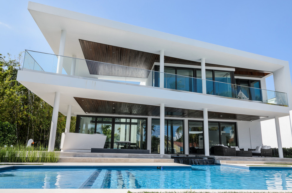 Esempio di un'ampia piscina moderna personalizzata dietro casa con una vasca idromassaggio e piastrelle