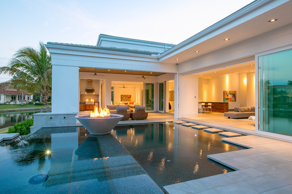 This is an example of a small contemporary back rectangular infinity swimming pool in Tampa with concrete slabs.