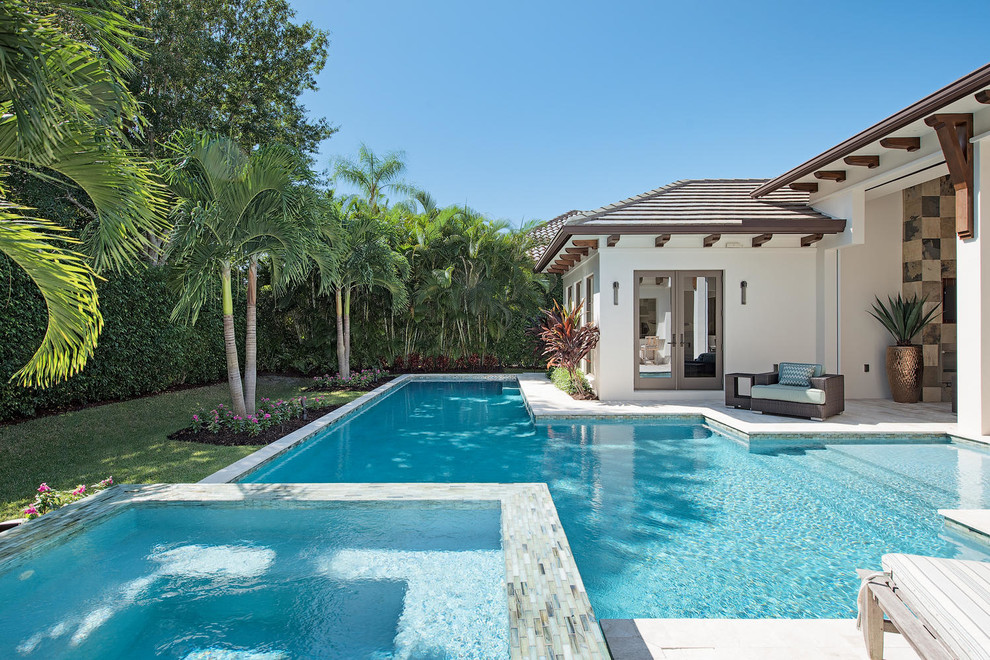 Foto di un'ampia piscina monocorsia classica personalizzata dietro casa con una vasca idromassaggio e pavimentazioni in pietra naturale