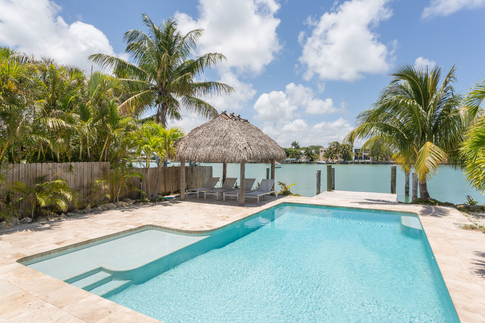 Foto di una piscina monocorsia tropicale a "L" dietro casa con pavimentazioni in pietra naturale