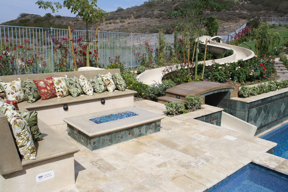 Immagine di un'ampia piscina mediterranea rettangolare dietro casa con un acquascivolo e pavimentazioni in pietra naturale