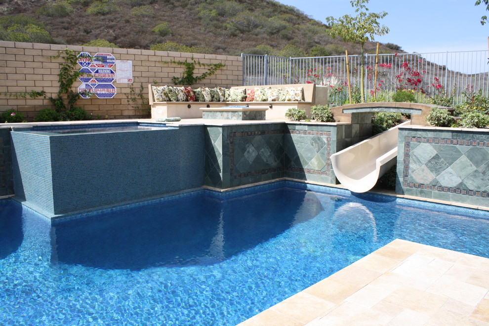 Ispirazione per un'ampia piscina mediterranea rettangolare dietro casa con un acquascivolo e pavimentazioni in pietra naturale