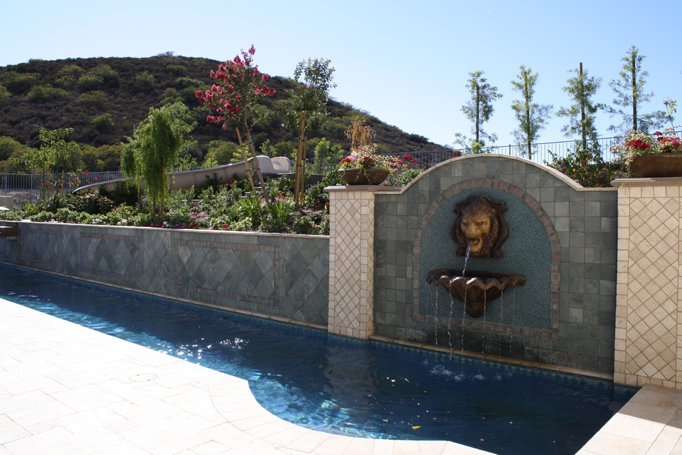 Ejemplo de piscina con fuente mediterránea extra grande rectangular en patio trasero con adoquines de piedra natural
