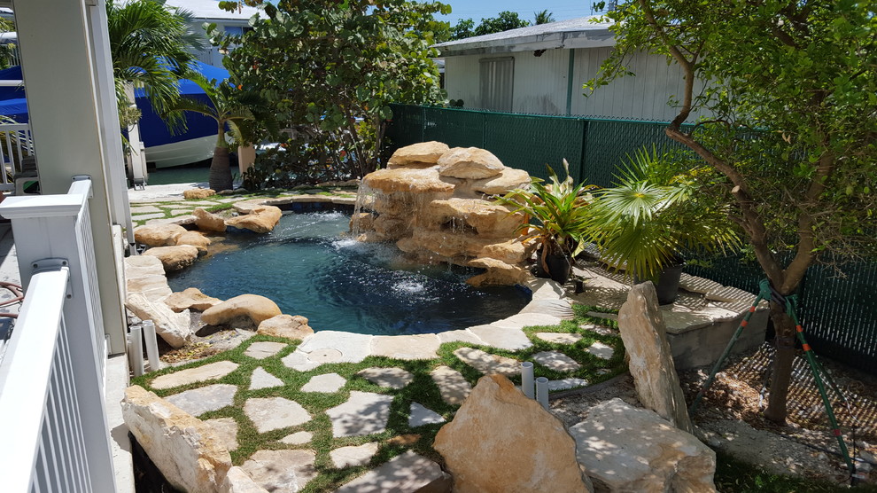 Cette photo montre une petite piscine naturelle et arrière exotique sur mesure avec un point d'eau et des pavés en pierre naturelle.