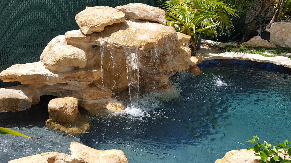 Diseño de piscina con fuente natural tropical pequeña a medida en patio trasero con adoquines de piedra natural