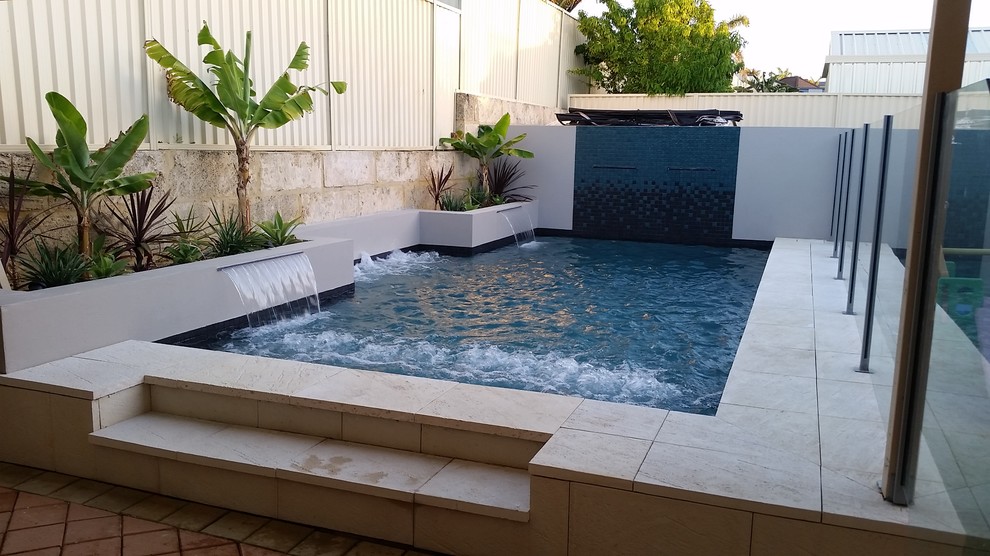 Aménagement d'une piscine naturelle et arrière exotique de taille moyenne et rectangle avec un point d'eau et des pavés en béton.