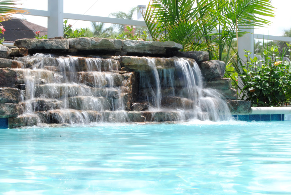 Photo of a coastal back rectangular lengths swimming pool in Miami with a water feature and brick paving.