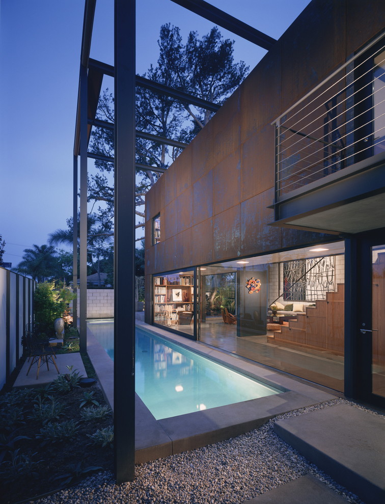 Diseño de piscina alargada moderna rectangular en patio lateral con losas de hormigón