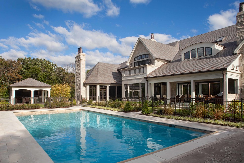 Ispirazione per una piscina tradizionale rettangolare di medie dimensioni e dietro casa con una dépendance a bordo piscina e pavimentazioni in pietra naturale