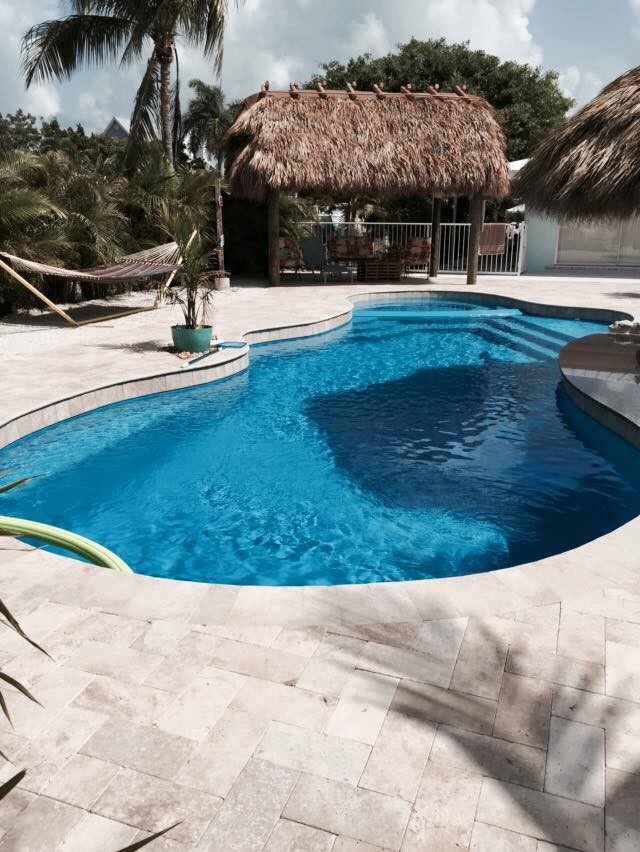 Großer Schwimmteich hinter dem Haus in individueller Form mit Natursteinplatten in Miami