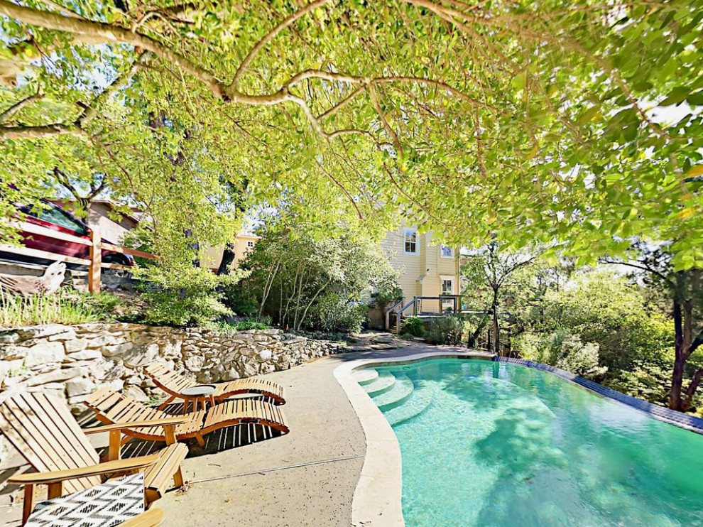 Foto de piscina natural ecléctica de tamaño medio tipo riñón en patio lateral con paisajismo de piscina y entablado