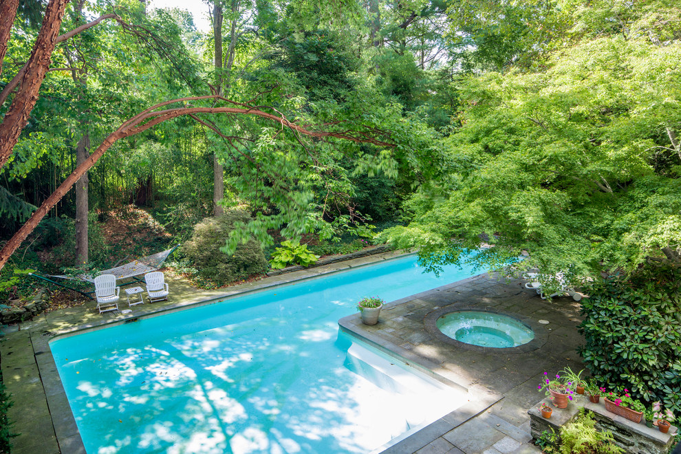 Traditional back l-shaped swimming pool in Philadelphia with natural stone paving.