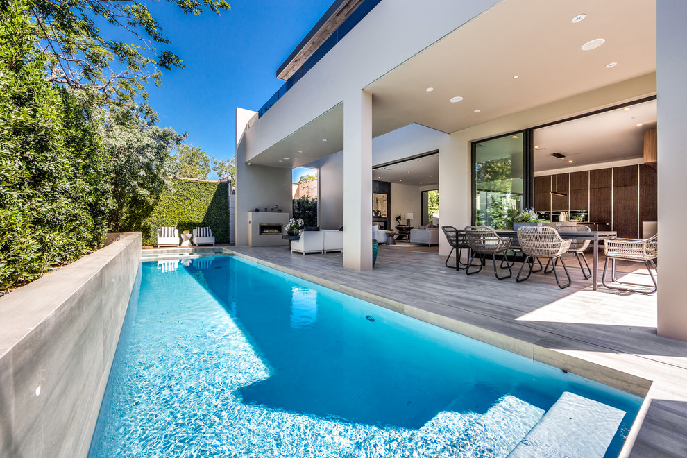 Diseño de piscina con fuente alargada minimalista rectangular en patio trasero con suelo de baldosas