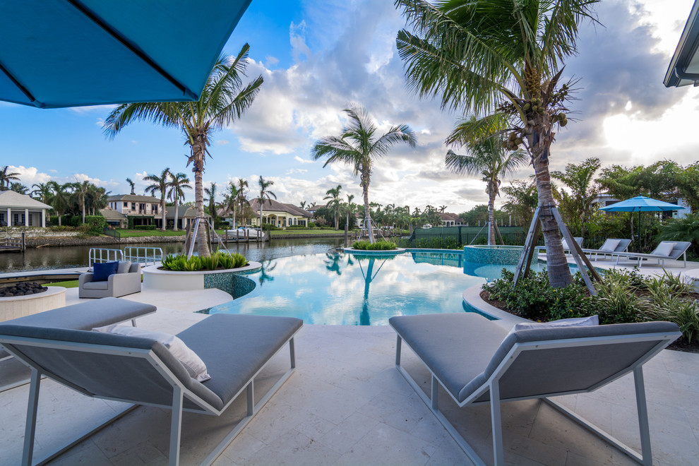 Large transitional backyard custom-shaped infinity pool photo in Miami