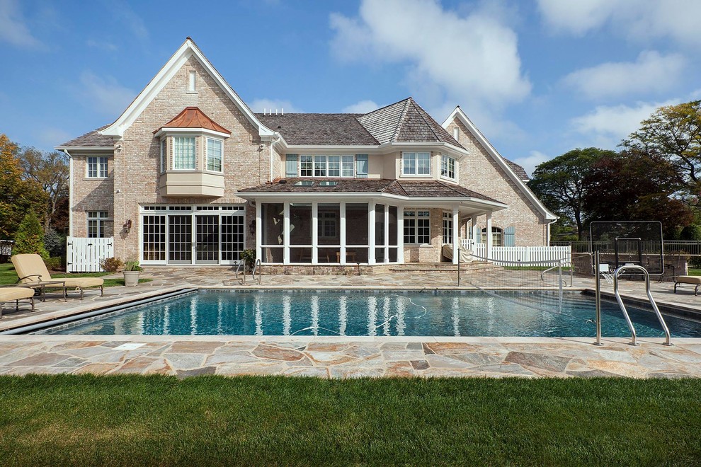 Foto de piscina alargada clásica grande rectangular en patio trasero con adoquines de piedra natural