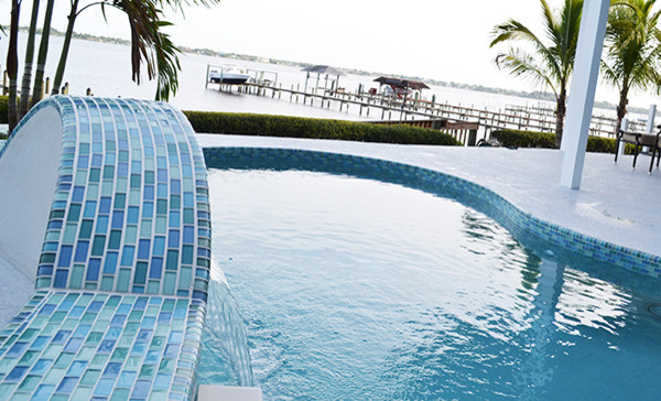 Back swimming pool in Miami with a water feature and tiled flooring.