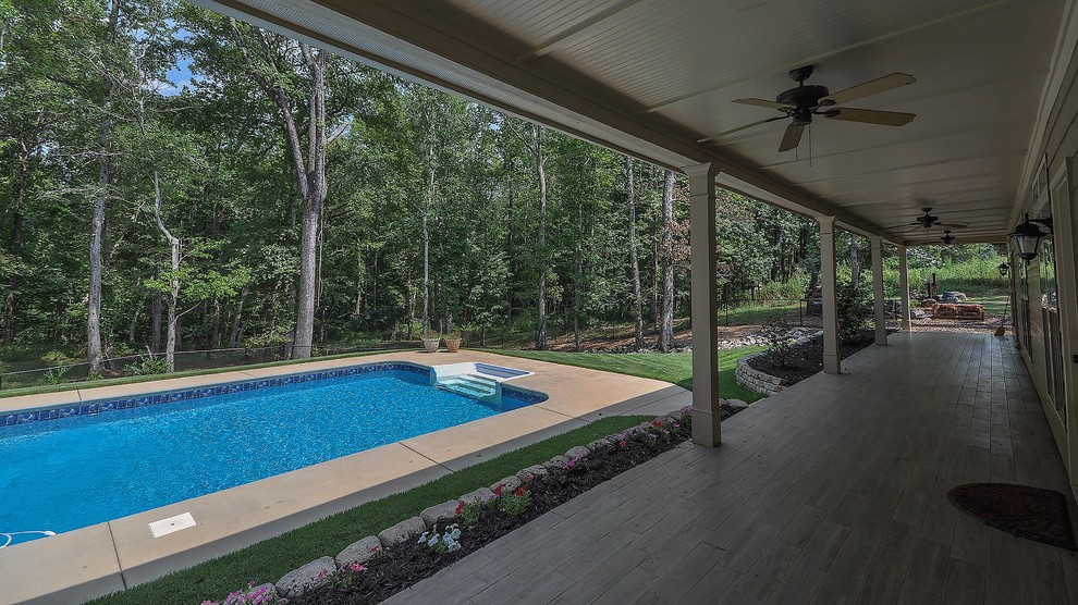 Foto de piscina natural de estilo americano grande rectangular en patio trasero con adoquines de hormigón