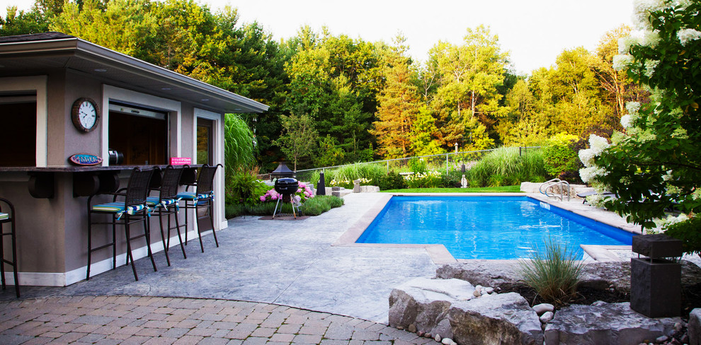Inspiration for a large world-inspired back rectangular lengths swimming pool in Toronto with a pool house and stamped concrete.
