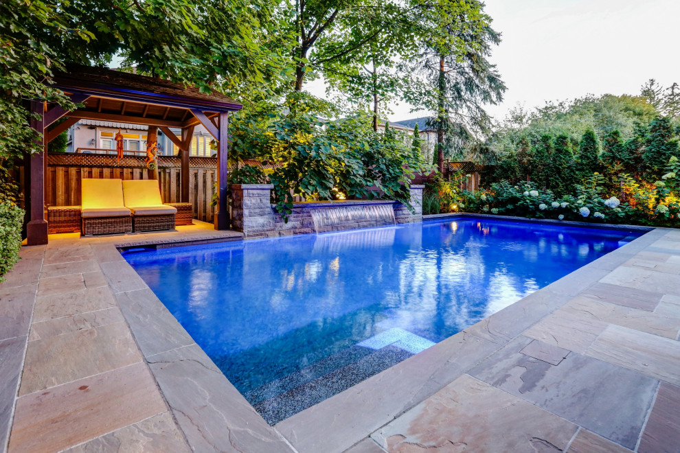 Foto de piscina con fuente tradicional renovada de tamaño medio rectangular en patio trasero con adoquines de piedra natural