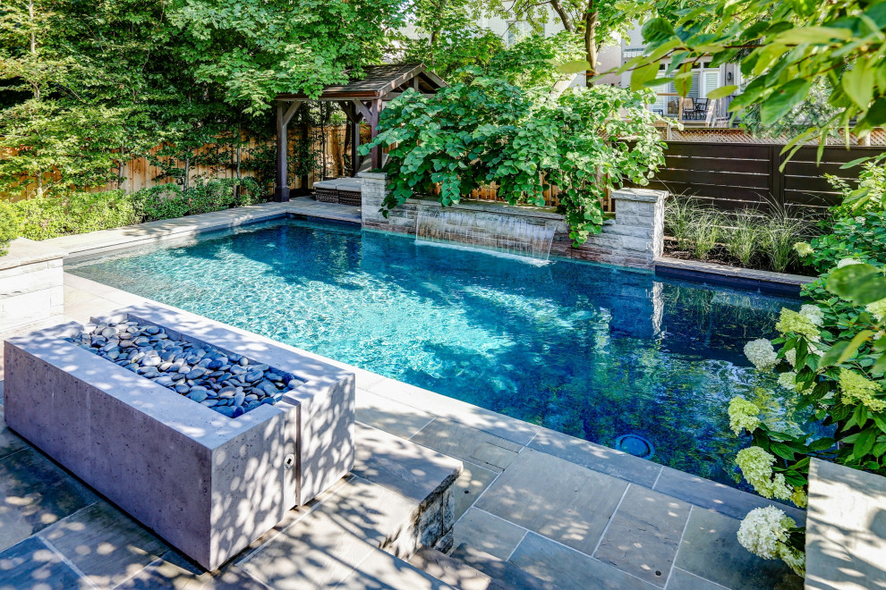 Réalisation d'une piscine arrière tradition de taille moyenne et rectangle avec des solutions pour vis-à-vis et des pavés en pierre naturelle.