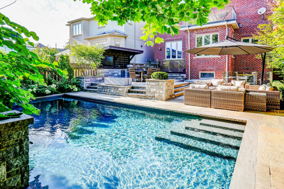 Mid-sized transitional backyard stone and rectangular pool landscaping photo in Toronto