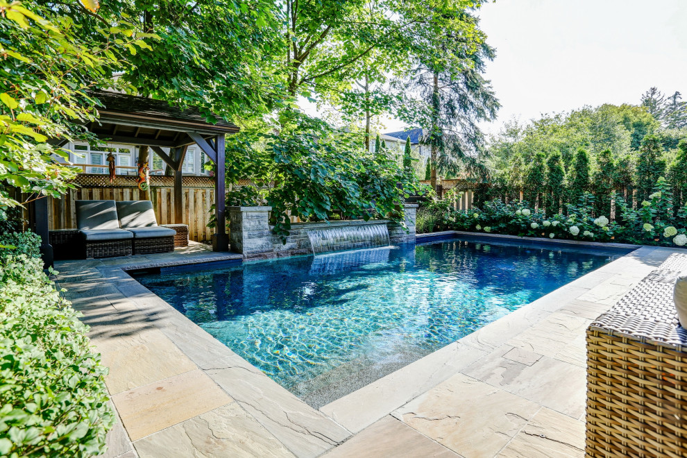 Ejemplo de piscina con fuente tradicional renovada de tamaño medio rectangular en patio trasero con adoquines de piedra natural
